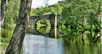 Casco histórico de Allariz junto al río Arnoia, con el puente y las casas de piedra reflejadas en el agua