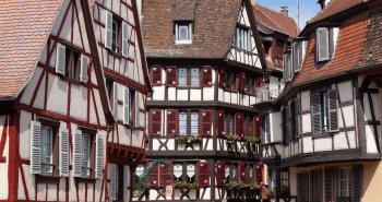 Casas de entramado de madera y colores junto a un canal florido en Colmar, Alsacia