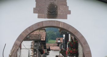 Calle principal de Amaiur con sus caseríos blasonados del valle de Baztan y colinas verdes al fondo
