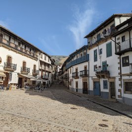 Calle empinada de Candelario con casas serranas de piedra y la Sierra de Béjar al fondo