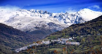 Casas blancas de Capileira escalonadas en la ladera del Barranco de Poqueira, con las cumbres de Sierra Nevada al fondo