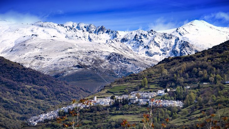 Casas blancas de Capileira escalonadas en la ladera del Barranco de Poqueira, con las cumbres de Sierra Nevada al fondo