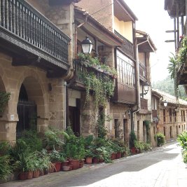 Calle empedrada de Cartes con sus torreones medievales y casonas de balcones de madera