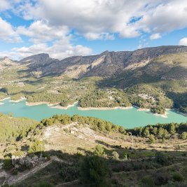 Vista panorámica del Castell de Guadalest con el campanario blanco sobre la peña y el embalse turquesa al fondo