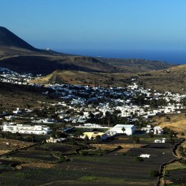 Vista panorámica del valle de las mil palmeras de Haría, con casas blancas entre palmerales y montañas volcánicas, en Lanzarote