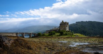 Castillo de Eilean Donan reflejado en el lago al atardecer, Highlands de Escocia