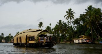 Casa flotante navegando entre palmeras por los backwaters de Kerala, en la India