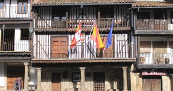 Calle empedrada de La Alberca con casas serranas de entramado de madera y balcones con flores