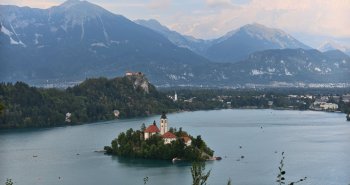Isla con iglesia en el lago Bled rodeada de montañas de los Alpes Julianos