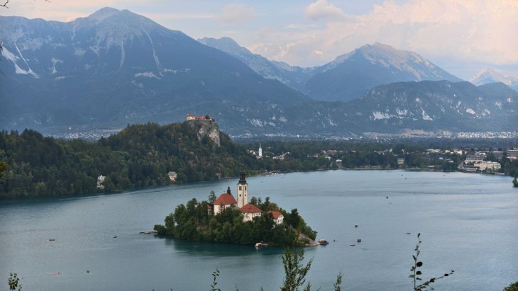 Isla con iglesia en el lago Bled rodeada de montañas de los Alpes Julianos