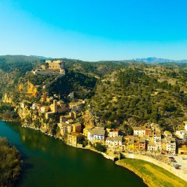 Panorámica de Miravet con sus casas sobre el río Ebro y el castillo templario en la cima