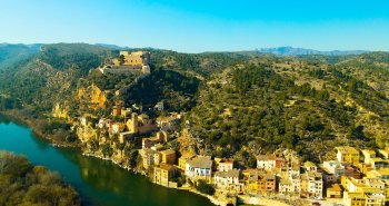 Panorámica de Miravet con sus casas sobre el río Ebro y el castillo templario en la cima
