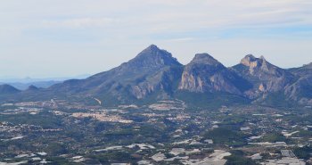 Vista panorámica de Polop de la Marina sobre su colina, con la sierra del Ponoig al fondo