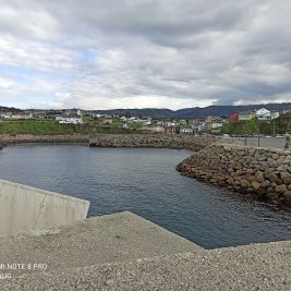 Puerto pesquero de Puerto de Vega en Asturias, con lanchas amarradas al abrigo del dique y casas marineras al fondo