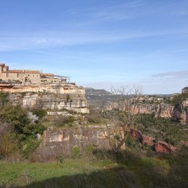 Vista de Siurana en lo alto de su risco calizo con el embalse turquesa al fondo