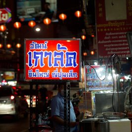 Puesto de comida callejera humeante en una calle de Bangkok