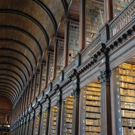 Sala histórica de una biblioteca con estanterías de madera repletas de libros antiguos