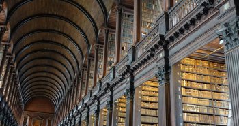 Sala histórica de una biblioteca con estanterías de madera repletas de libros antiguos