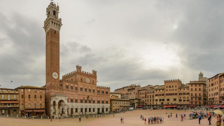Gran plaza histórica europea rodeada de fachadas antiguas y llena de ambiente