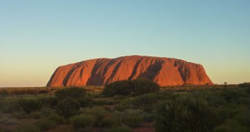 El monolito de Uluru teñido de rojo al atardecer en el desierto australiano