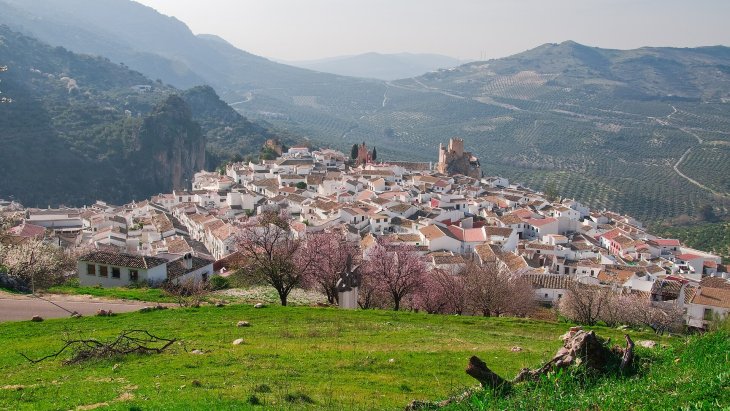 Panorámica de Zuheros con su castillo sobre la roca y las casas blancas asomadas al mar de olivos de la Subbética